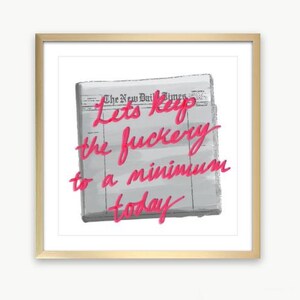 以下が含まれることがあります： ピンク色の「Let's keep the fuckery to a minimum today」というテキストが新聞の背景に印刷された額入りのプリント。タイプライター、椅子、鉢植えの植物がある机の上にプリントが飾られています。