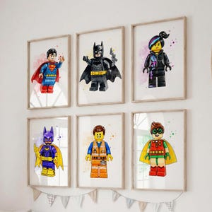 Peut inclure: Un ensemble de six cadres muraux présentant des illustrations style aquarelle de figurines type Lego, incluant Superman, Batman, Wyldstyle, Batgirl, Emmet et Robin, chacune affichée en orientation verticale sur un fond blanc.