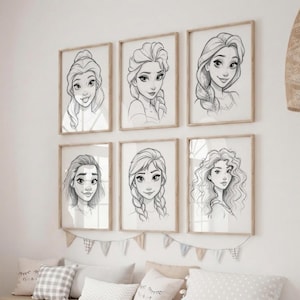 Op de afbeelding: Zes ingelijste potloodschetskunstdrukken van geanimeerde vrouwelijke personages met verschillende kapsels. De prints zitten in lichtbruine houten frames en hangen aan een witte muur. Een decoratieve banner en kussens zijn hieronder zichtbaar.