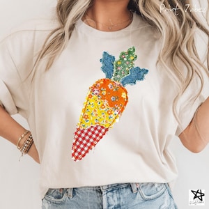 May include: A cream-coloured t-shirt with a patchwork carrot design. The carrot is made from various fabric patterns, including floral, gingham, and denim. The design is centred on the shirt, with the text "Print 7vibes" in the upper right corner.