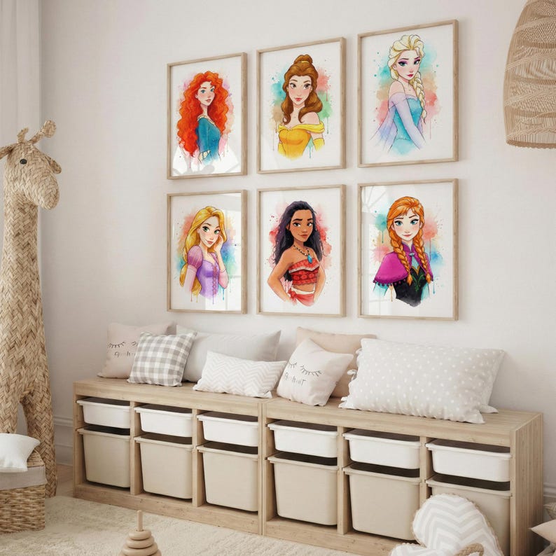 May include: Six framed watercolor prints of Disney princesses hang on a white wall. The artwork features vibrant colors and depicts characters like Elsa, Belle, and Ariel. Below, a wooden storage unit with white bins and decorative pillows.