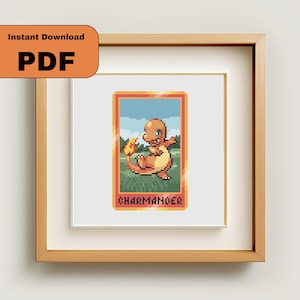 May include: A framed cross-stitch featuring a pixelated Charmander character. The artwork is set against a white background, framed in a light wood. The image includes the text "Instant Download PDF".
