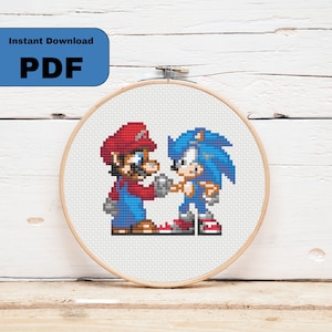 May include: Cross stitch pattern featuring Mario and Sonic the Hedgehog, both in their classic video game styles. The pattern is in a circular embroidery hoop.