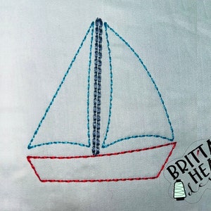 Può includere: Un semplice disegno di barca a vela ricamato con una vela blu e uno scafo rosso. Il disegno è ricamato su uno sfondo di tessuto bianco.