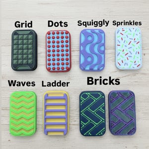May include: A collection of eight rectangular decorative items with various patterns and colors. Designs include grids, dots, squiggly lines, sprinkles, waves, ladders, and brick patterns. Each item has a different color scheme, with text labels.