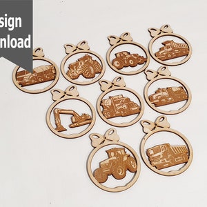 Può includere: Dieci ornamenti in legno con diversi veicoli da costruzione, tra cui un trattore, un camion ribaltabile, un escavatore e un camion con rimorchio. Ogni ornamento ha la forma di un cerchio con un fiocco in cima.