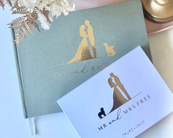 Peut inclure: Deux livres d'or de mariage avec des accents dorés. Le livre vert a une silhouette d'un couple et d'un chien. Le livre blanc a une silhouette d'un couple et d'un chien avec le texte "MR and MRS FREE 26.02.2022".