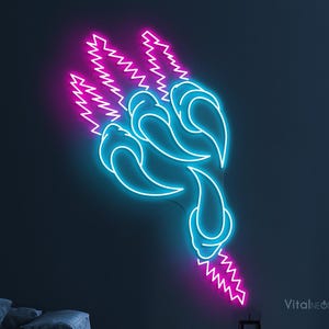 May include: A neon sign featuring a blue paw print with pink lightning bolts. The sign is mounted on a dark wall with a sofa and a table in the background.
