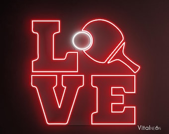 May include: Red neon sign with the word "LOVE" with a ping pong paddle and ball in the "O". The sign is mounted on a dark wall with a wooden chair and table in the foreground.