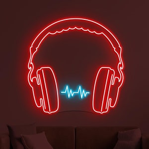 May include: Red neon sign of headphones with a blue neon sound wave in the middle. The sign is mounted on a dark wall above a brown sofa.