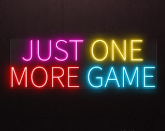 Puede incluir: Letrero de neón con las palabras "JUST ONE MORE GAME" en rosa brillante, amarillo, rojo y azul. El letrero está montado en una pared gris oscuro, creando un contraste llamativo. Las luces de neón son vibrantes y llamativas.