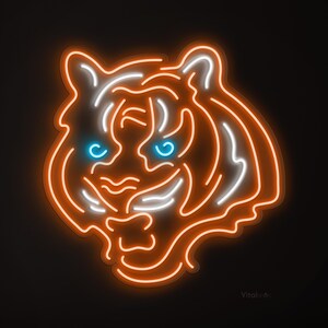 May include: Neon sign in the shape of a tiger's head. The tiger's face is outlined in orange neon, with white and blue accents. The eyes are a bright blue. The background is black.