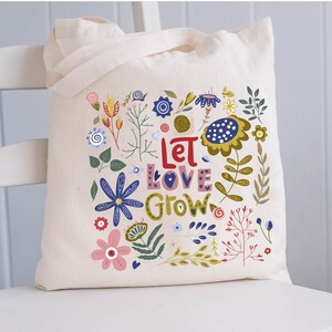 May include: A white canvas tote bag with a floral design and the text "Let Love Grow". The flowers are in shades of blue, red, yellow, and green.