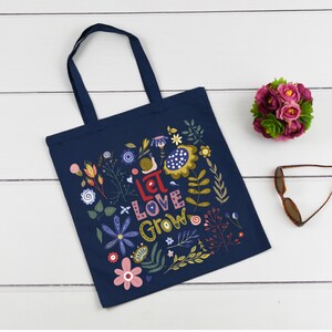 May include: A navy blue tote bag with a floral design and the text "Let Love Grow".