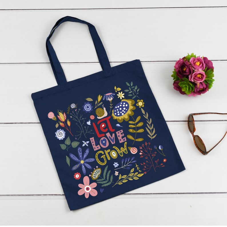 May include: A navy blue tote bag with a floral design and the text "Let Love Grow".