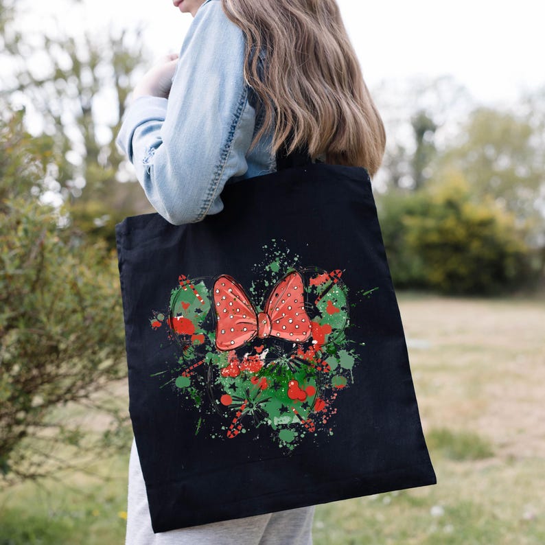 Puede incluir: Bolsa de tela negra con un lazo rojo y blanco con lunares y salpicaduras de pintura verde y negra.