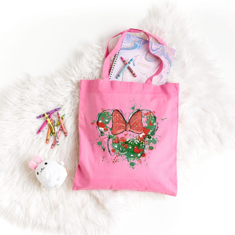 Puede incluir: Bolsa de lona rosa con un gr&aacute;fico verde y rojo de una cabeza de rat&oacute;n de dibujos animados con un lazo. El gr&aacute;fico tiene un efecto de pintura salpicada.