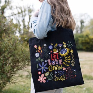 May include: Black tote bag with a floral design and the text "Let Love Grow".