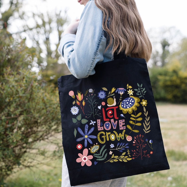 May include: Black tote bag with a floral design and the text "Let Love Grow".