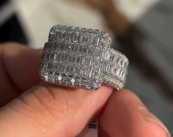 May include: A silver ring with a square-shaped top set with baguette-cut diamonds.