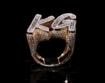 Può includere: Un anello d'oro con le lettere "KG" incastonate con diamanti. L'anello è in oro 14 carati e ha una montatura pavé.