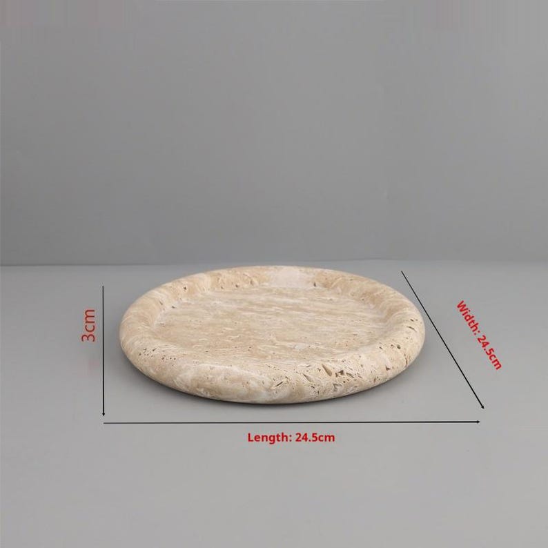 May include: A round, beige stone tray. The tray is 24.5 cm in diameter and 3 cm thick. The surface has a textured, natural appearance. The tray is suitable for serving food or as a decorative item.
