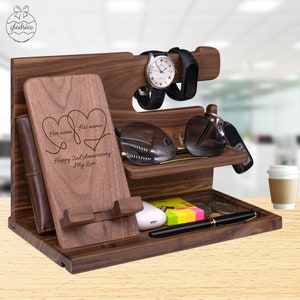 May include: A wooden desktop organizer with a phone stand, watch holder, sunglasses holder, and a small tray. The organizer is engraved with the text "Her name His name Happy 2nd Anniversary My Love".