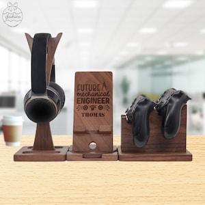 May include: Wooden stand with three compartments for organizing headphones, a phone, and two game controllers. The middle compartment has the text "FUTURE MECHANICAL ENGINEER THOMAS" engraved on it.