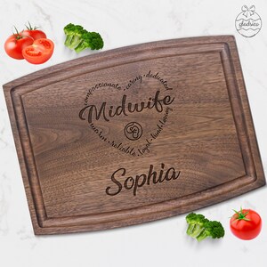 May include: A brown wooden cutting board with the text "compassionate, caring, dedicated, Midwife, warm, reliable, loyal, kind, loving" and the name "Sophia" engraved on it.