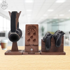 May include: Wooden stand with a personalized engraved message "Grandpa" and a bear design. The stand has three compartments for holding headphones, a phone, and two controllers.