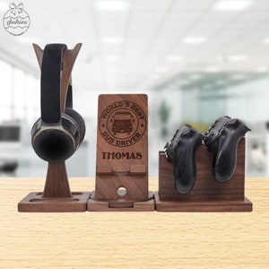 May include: A wooden stand with three compartments for organizing headphones, a phone, and two game controllers. The middle compartment has a personalized inscription that reads "World's Best Bus Driver Thomas".
