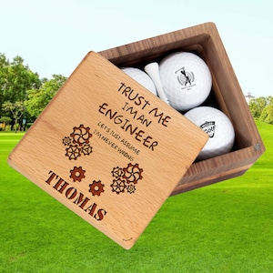 May include: Wooden box with a golf ball set. The box has a personalized message that reads "Trust me I'm an Engineer. Let's just assume I'm never wrong." The box also has the name "Thomas" engraved on it.