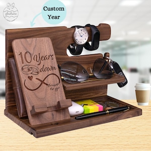 May include: A wooden organizer with a phone stand, watch holder, sunglasses holder, and a tray for keys and other small items. The organizer is engraved with the text "10 years down forever to go" and two rings.