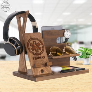 May include: A wooden organizer with a phone stand, headphone holder, watch holder, sunglasses holder, and a small shelf for other items. The organizer is engraved with the words "Emergency Medical Services" and "Thomas".