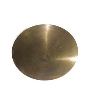 Puede incluir: Una bandeja redonda de metal de color lat&oacute;n con una superficie ligeramente abovedada.