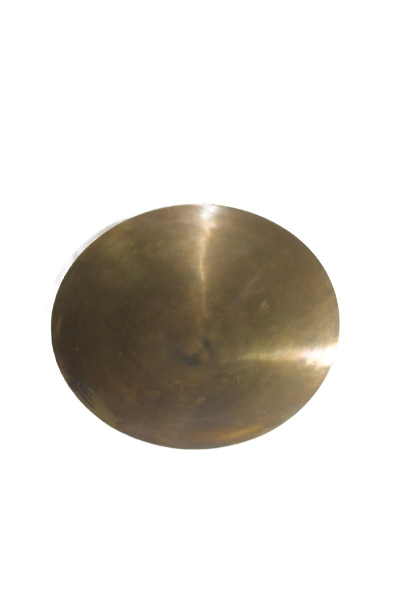 Puede incluir: Una bandeja redonda de metal de color lat&oacute;n con una superficie ligeramente abovedada.