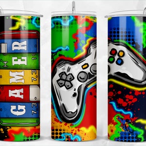 May include: Three colorful gamer themed tumblers with a black background. The first tumbler has the word "GAMER" in colorful letters. The second tumbler has a white video game controller with neon green, blue, and red accents. The third tumbler has a white video game controller with neon green, blue, and red accents and a black and white polka dot pattern.