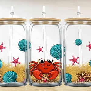 May include: Three clear glass jars with bamboo lids and straws. Each jar has a different design featuring a red crab, blue seashells, and pink starfish on a gold glitter background with a leopard print pattern.