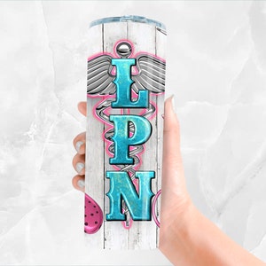 May include: White stainless steel tumbler with a wood grain pattern. The tumbler features a blue and pink medical caduceus symbol with the letters "LPN" in the center.