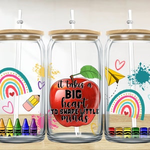 Peut inclure: Trois verres à boire en verre transparent avec des couvercles en bambou et des pailles. Chaque verre présente un motif différent : un arc-en-ciel, une pomme avec le texte « il faut un grand cœur pour façonner les petits esprits » et un arc-en-ciel avec un avion en papier. Chaque verre a également une rangée de crayons de couleur en bas.