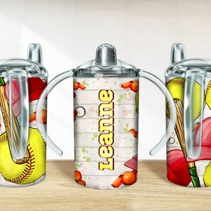Könnte beinhalten: Ein Edelstahl-Trinkbecher mit Sportmotiv. Der Becher hat ein Design aus Softbällen, Baseballschlägern und roten Baseballkappen. Der Name "Leanne" ist vertikal auf dem Becher aufgedruckt. Der Becher hat zwei Griffe.