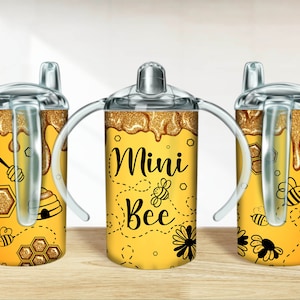 May include: Three yellow and black mini bee themed sippy cups with lids and straws. The cups have a glitter finish and feature a honeycomb design, bees, and the text "Mini Bee".