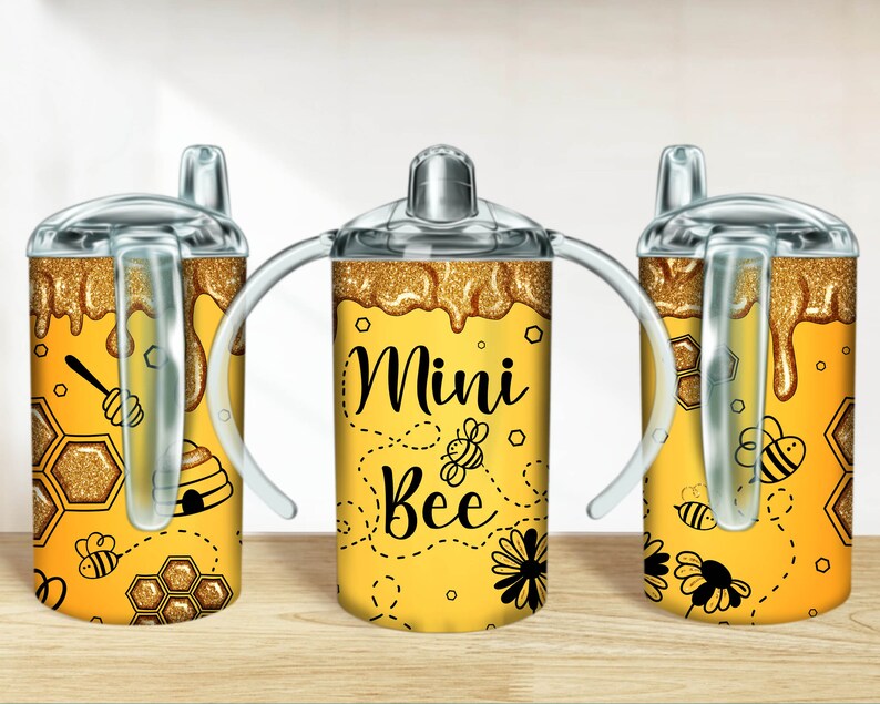 May include: Three yellow and black mini bee themed sippy cups with lids and straws. The cups have a glitter finish and feature a honeycomb design, bees, and the text "Mini Bee".