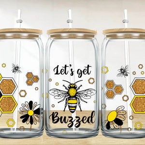 May include: Three glass jars with bamboo lids and straws. Each jar has a different design featuring a bee, honeycomb, and the text "Let's get buzzed".