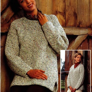 May include: A light gray knit sweater with flecks of color. The sweater has a round neck and long sleeves. The image also shows a smaller image of a similar sweater with a V-neck.