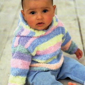 Könnte beinhalten: Ein Baby trägt einen gestreiften Kapuzenpullover in den Farben Rosa, Blau, Gelb und Grün. Der Pullover ist aus einem weichen, flauschigen Material. Das Baby trägt auch eine blaue Jeans.