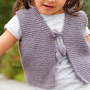 May include: A purple knitted vest with a tie closure and tassels. The vest is sleeveless and has a V-neck.