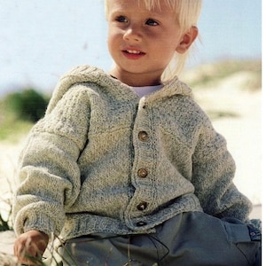 May include: A light green knitted hooded cardigan with wooden buttons. The cardigan is worn by a young child. The cardigan has a textured knit pattern and a button-up front. The child is wearing gray pants.
