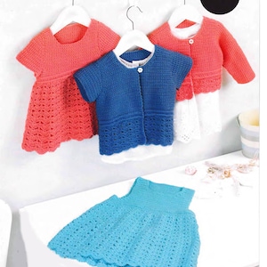 May include: Three crocheted baby dresses, one pink, one blue and one turquoise. The dresses are hanging on hangers and are displayed on a white surface. The word "Crochet" is printed in the top right corner of the image.