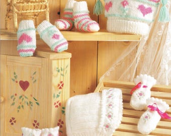 May include: A set of knitted baby clothes in pink and white, including a hat, booties, and mittens. The hat has a heart design and the booties and mittens have floral designs.